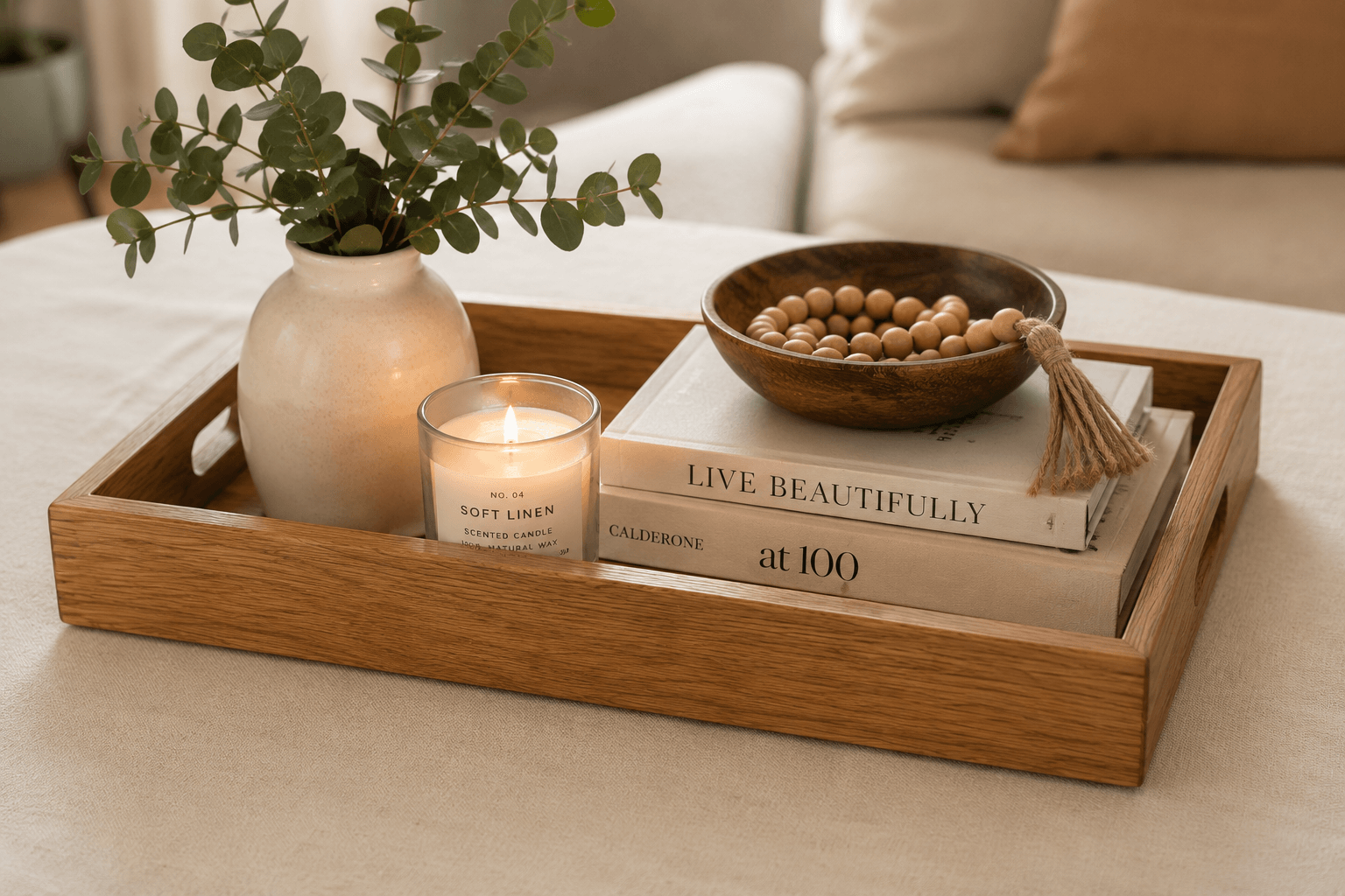 Wooden tray with a candle, books, bowl of beans, and vase on a table.