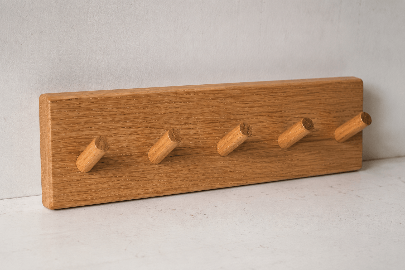 Wooden coat rack with five hooks on a light gray background